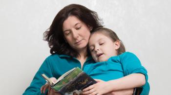 凯特琳躺在妈妈卡琳的腿上，卡琳给她读一本书。