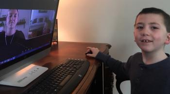 这是一张肯尼迪·克里格学院的学生在虚拟课堂上坐在电脑前的照片